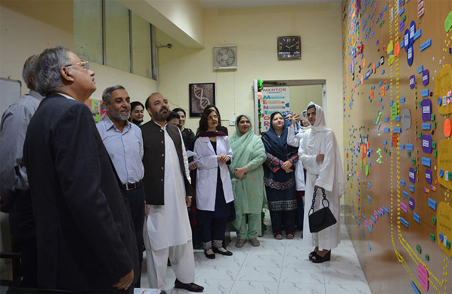 Fatahiya Kashif and students at the Federal Medical College in Islamabad gather in front of the metabolic pathways map.